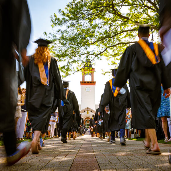 Graduates file down the quad path toward the Quinnipiac library during Commencement