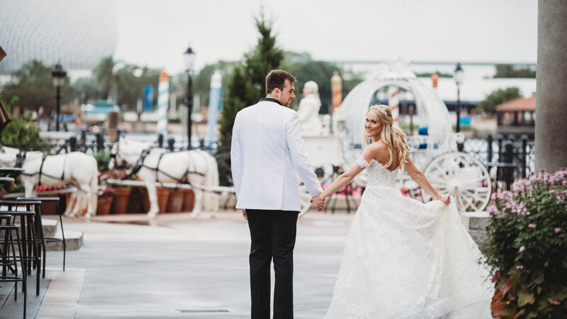 Rachel Davis-Marshall and Jacob Marshall walk hand in hand toward Cinderella's carriage on their wedding day