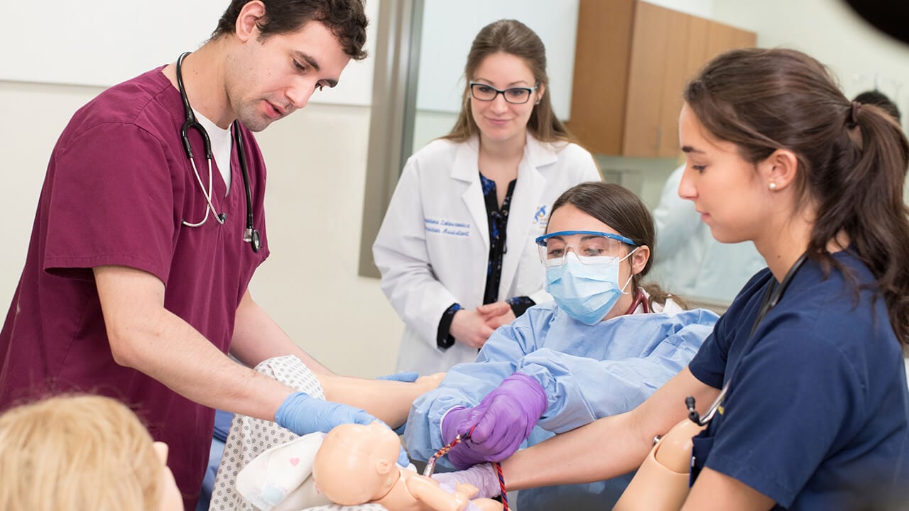 Collaborating to deliver a baby in the simulation lab are a DNP student, a physician assistant student and nursing student, along with a physician assistant faculty member.