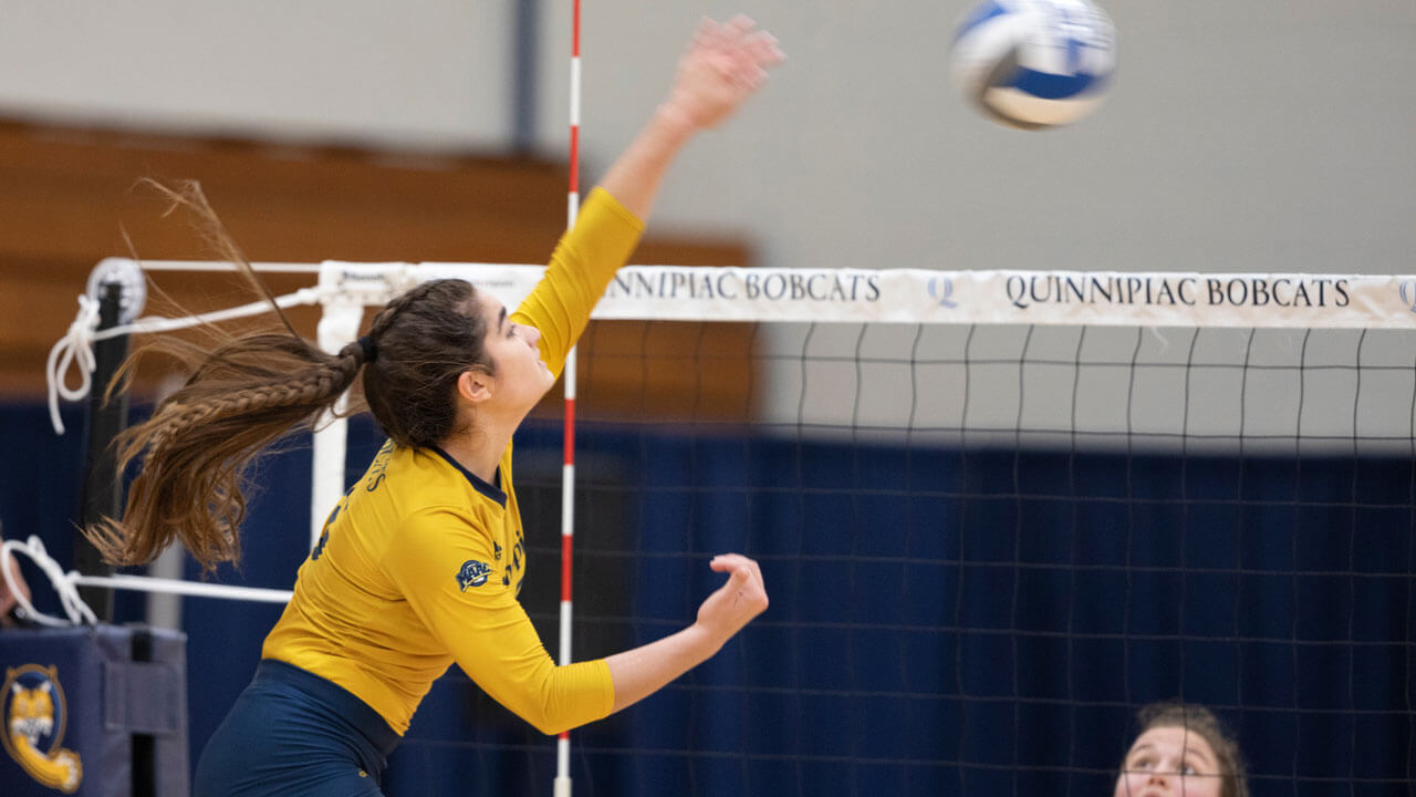 Women's volleyball player hitting ball over the net during bobcat weekend game