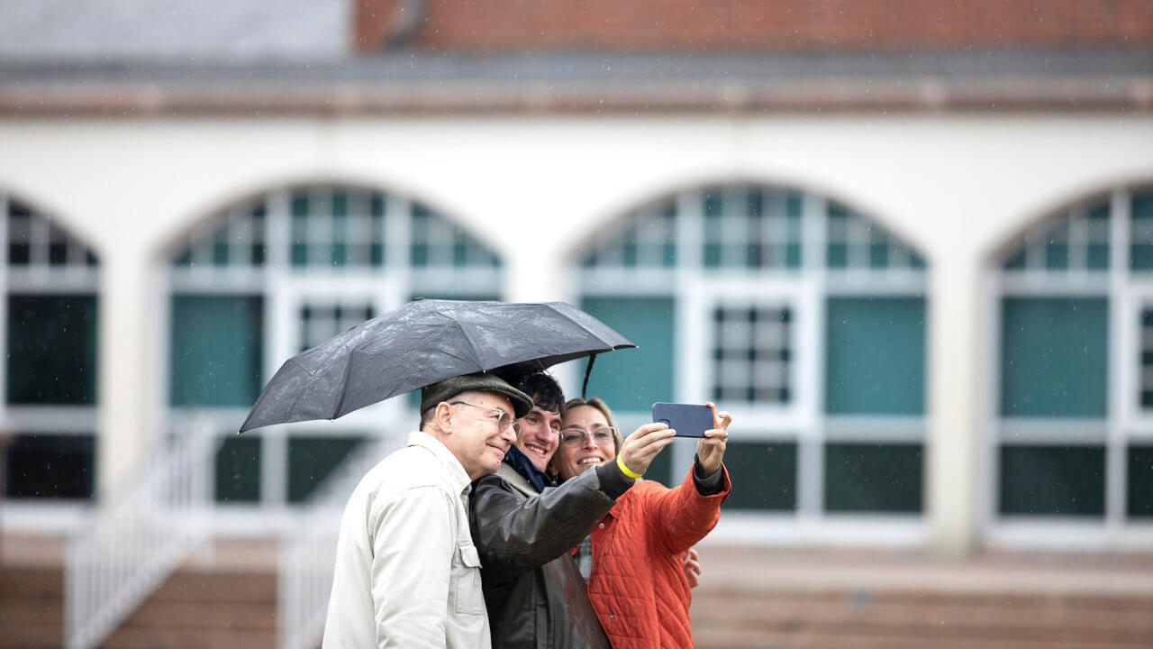 Student and parents taking a selfie outside on quad in front of library during bobcat weekend