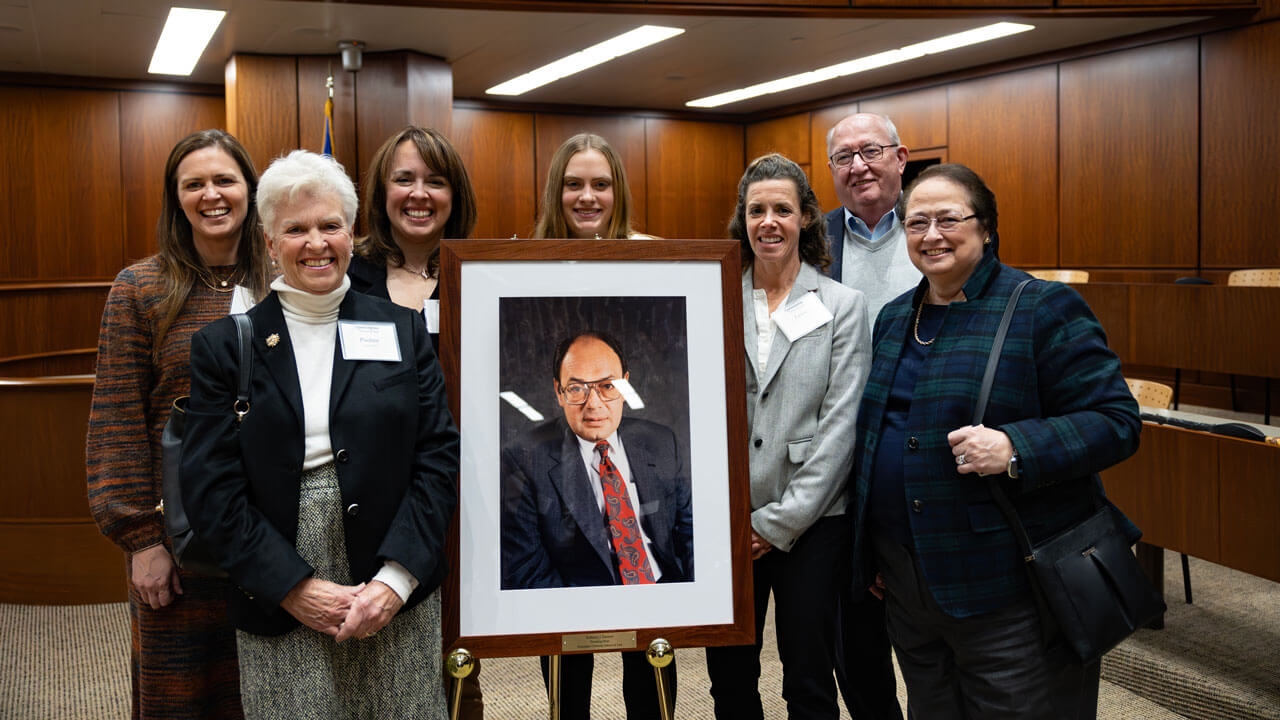 A group of inaugural alumni association award attendees pose with a picture frame.
