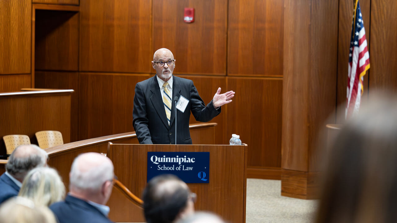 A speaker presents at the inaugural alumni association awards at a podium.