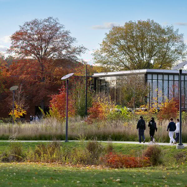 A group of students walk past the RecWell center on a blue sky fall day