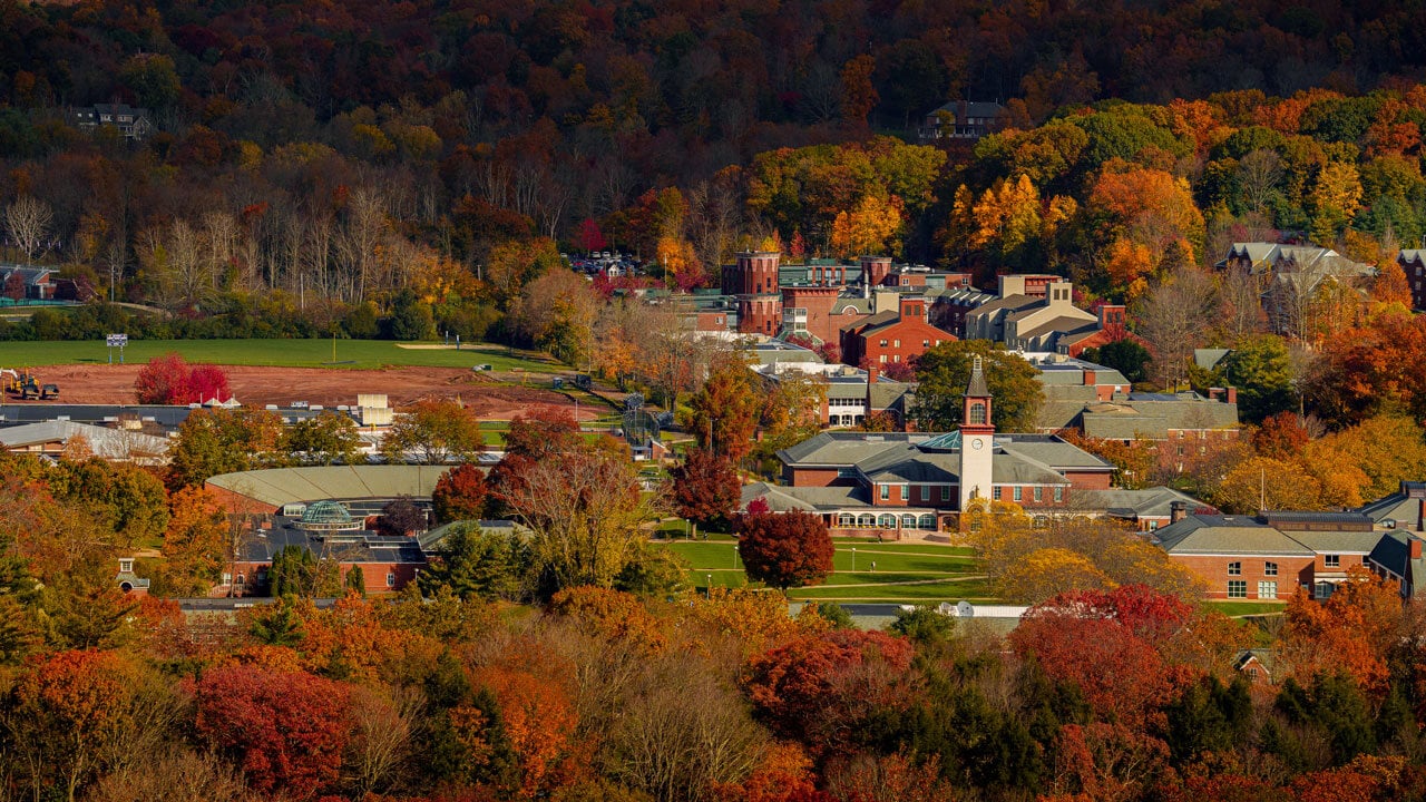 A wide shot of the Quinnipiac Mount Carmel campus during the autumn season with fall foliage and the clock tower.