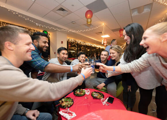Graduate students cheers glasses during the annual holiday dinner