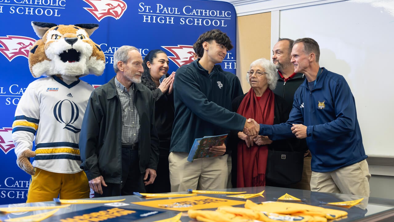 A new student surrounded by family shakes hands with Tom Ellett