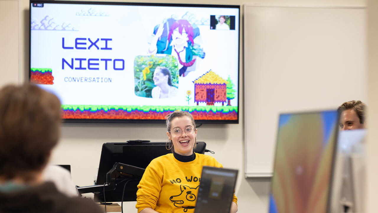 Lexi Nieto, an anime voice actress, speaks to a group of students with a presentation behind her.