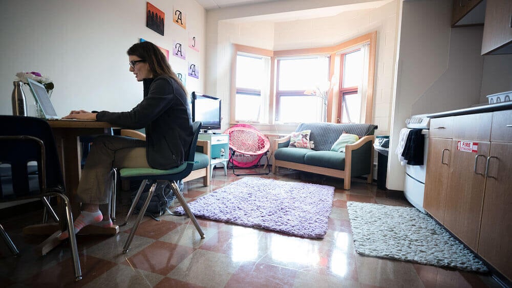 A student works at her laptop in the common room of her apartment in Crescent