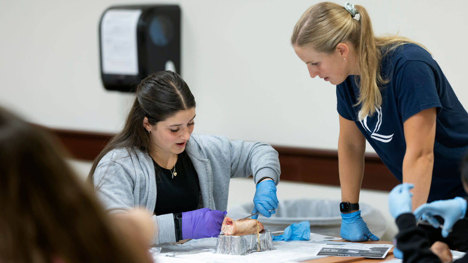 A high school student works with a Quinnipiac student during a health exploration camp.