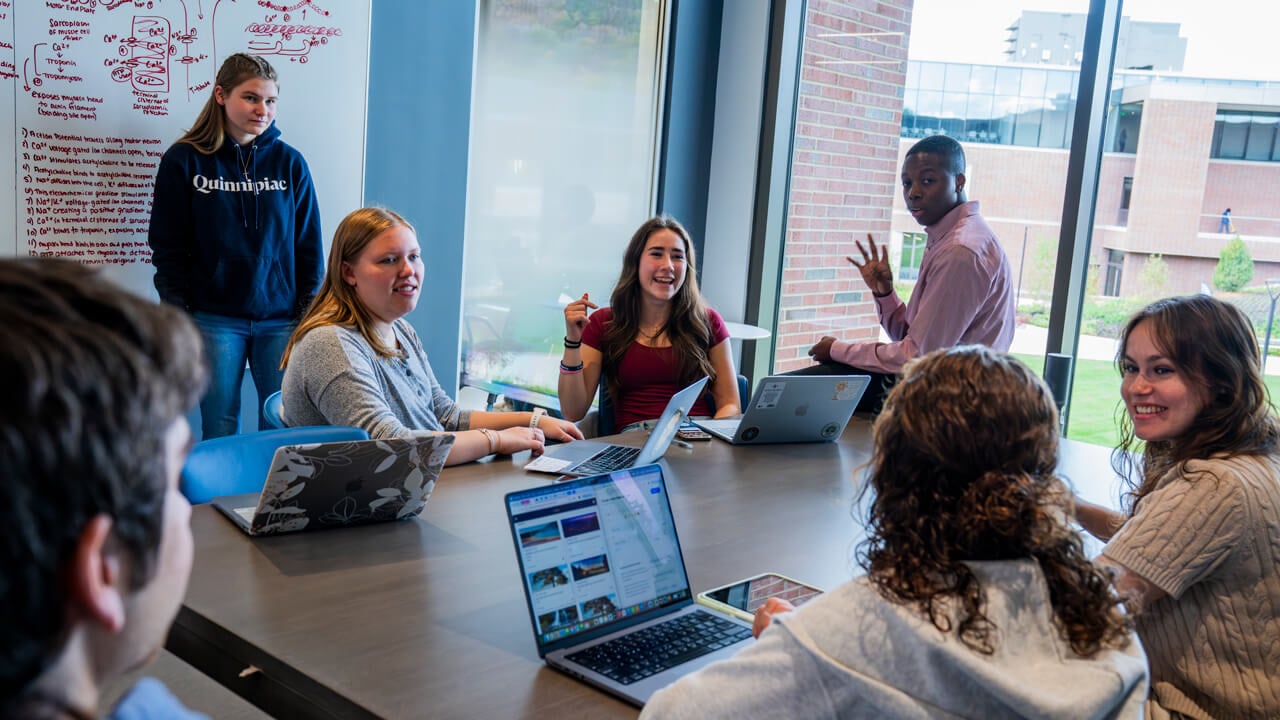 Six students talk and smile together as they study in a collaboration area