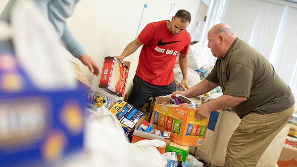 Two people sort through food donations made by Quinnipiac students, faculty and staff.