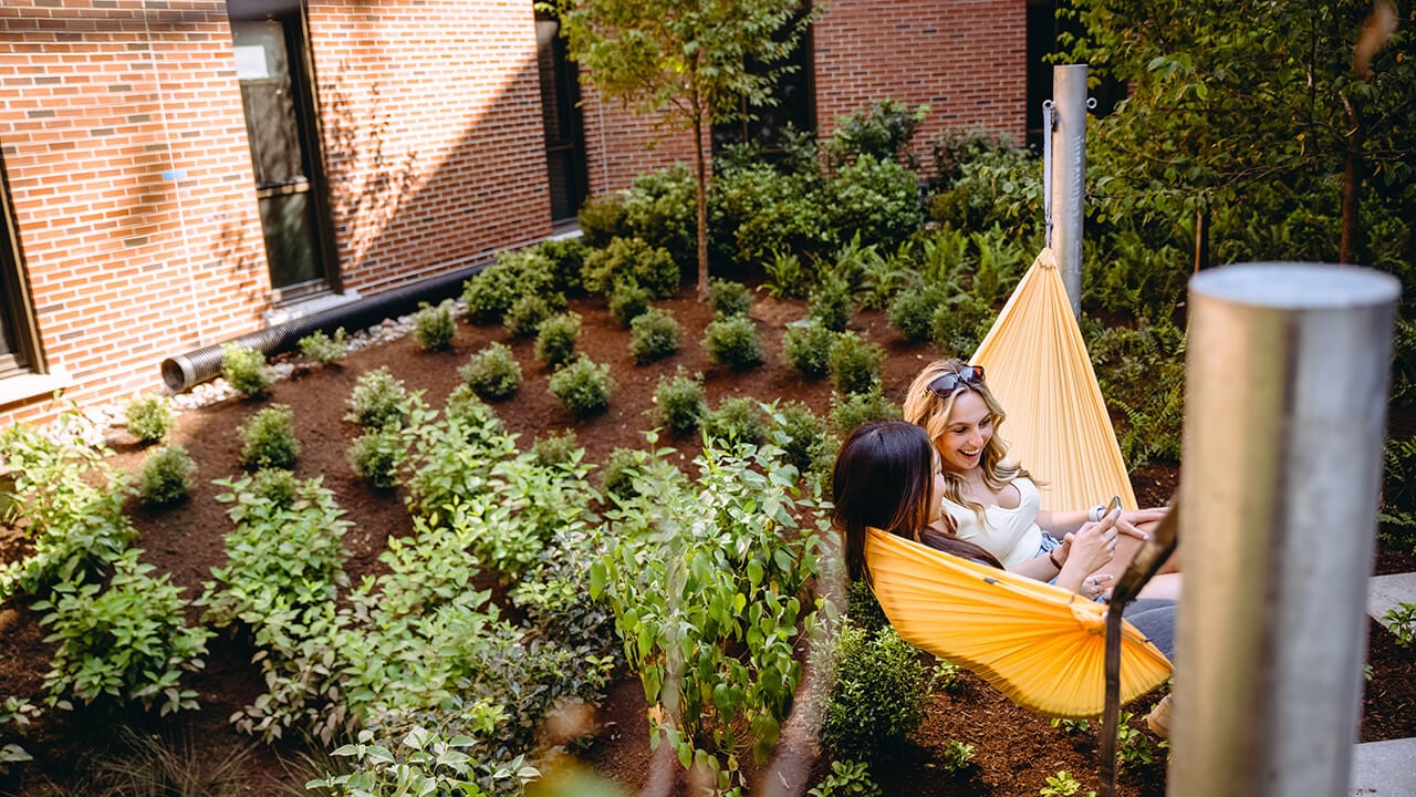 Two girls sitting in the hammocks outside of The Grove