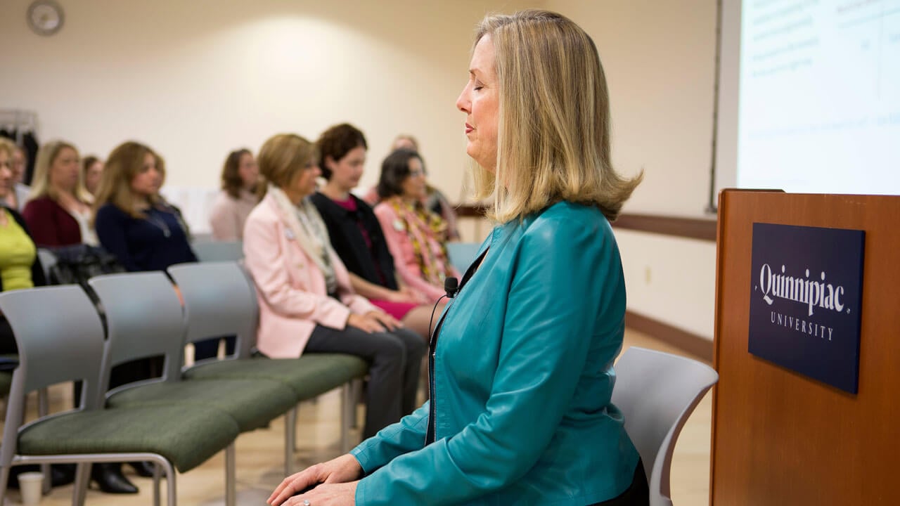 Cheryl Jones sits in a chair with her eyes closed leading a mindfulness exercise