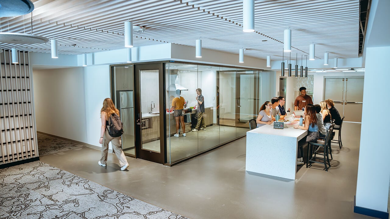 Students enjoy a meal together at a table in the grove common area.