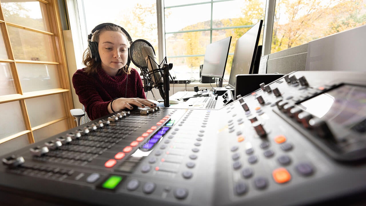 Student at the sound board in the School of Communications Podcast Studio