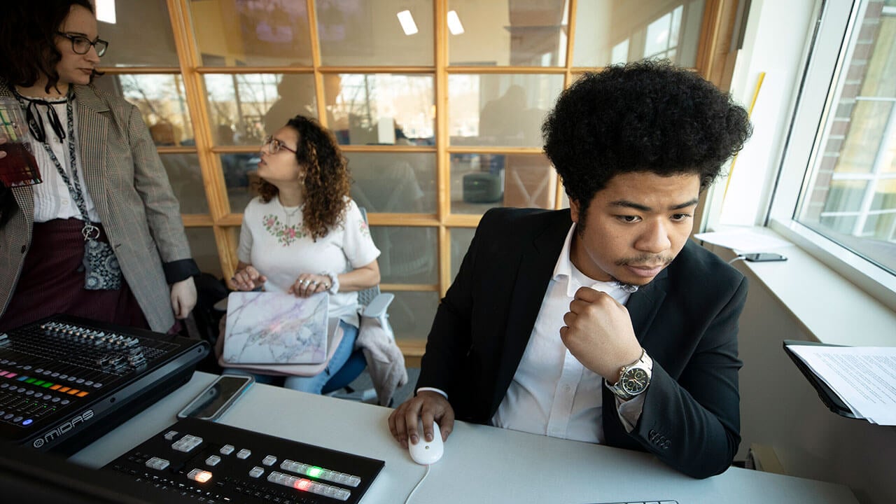 Student at the sound board in the School of Communications Podcast Studio