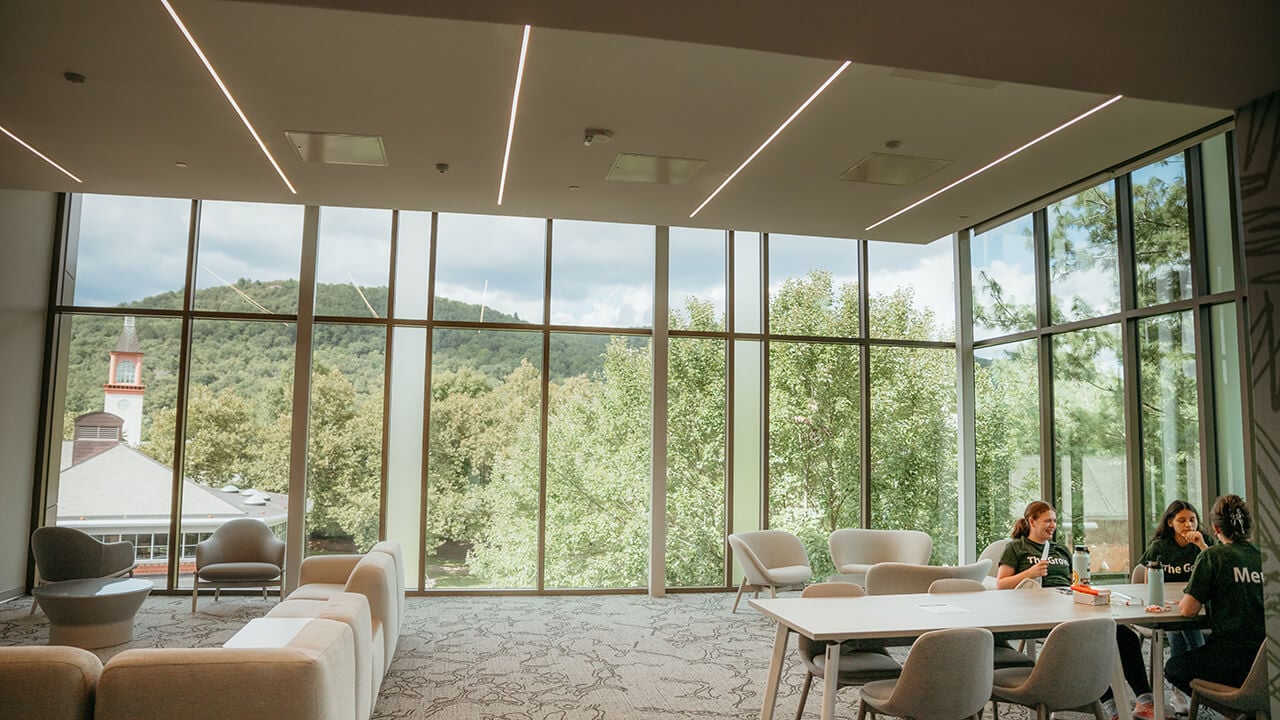 Students enjoy the view of the Arnold-Bernard Library and campus from The Grove lounge space