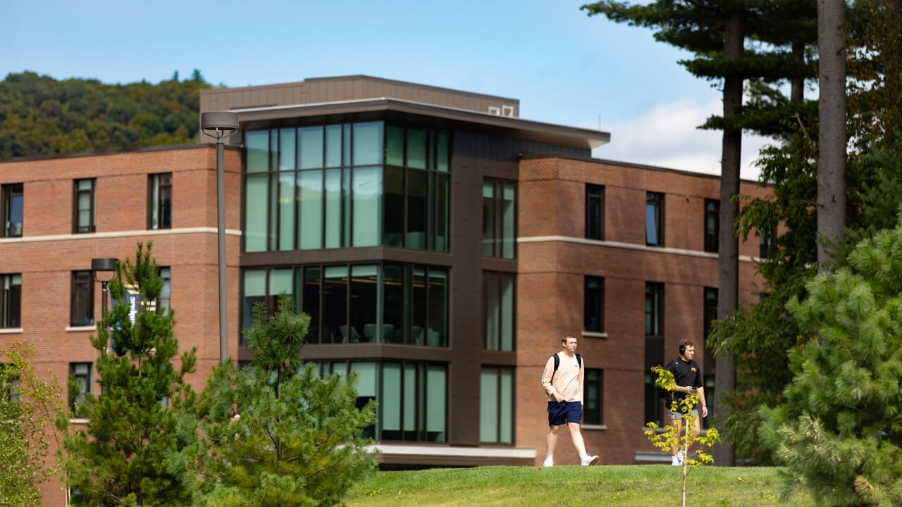 Two students walk in front of The Grove residence hall on a sunny day