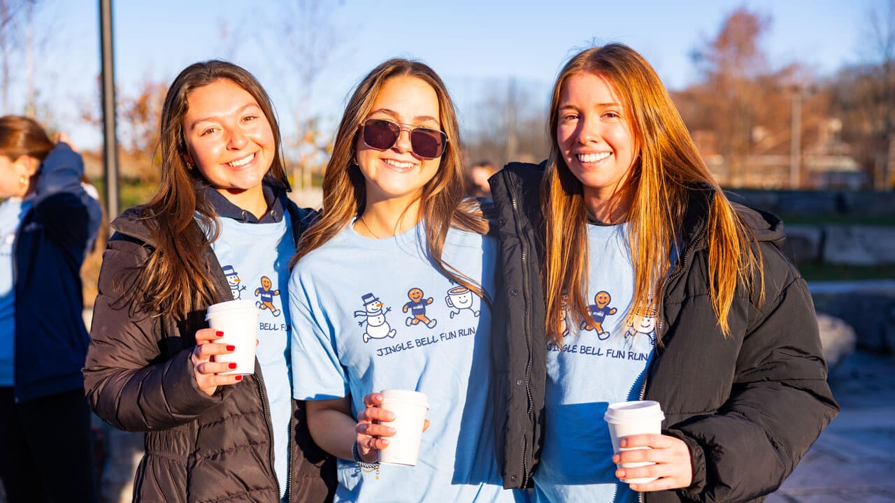 Three girls smile in Jingle Bell Fun Run t-shirts