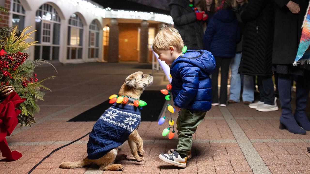 Child greets Tator the dog after the Quad Lighting