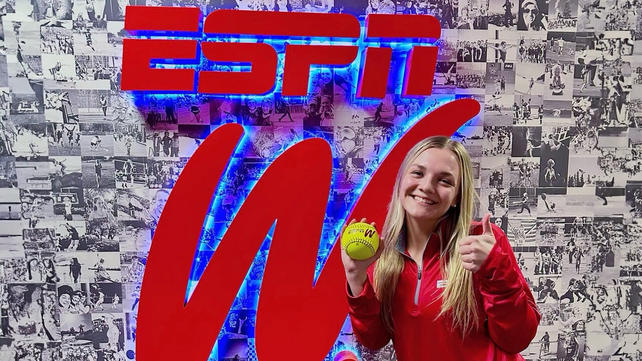 Lo Yarnall holding a softball and smiling in front of an ESPN W sign