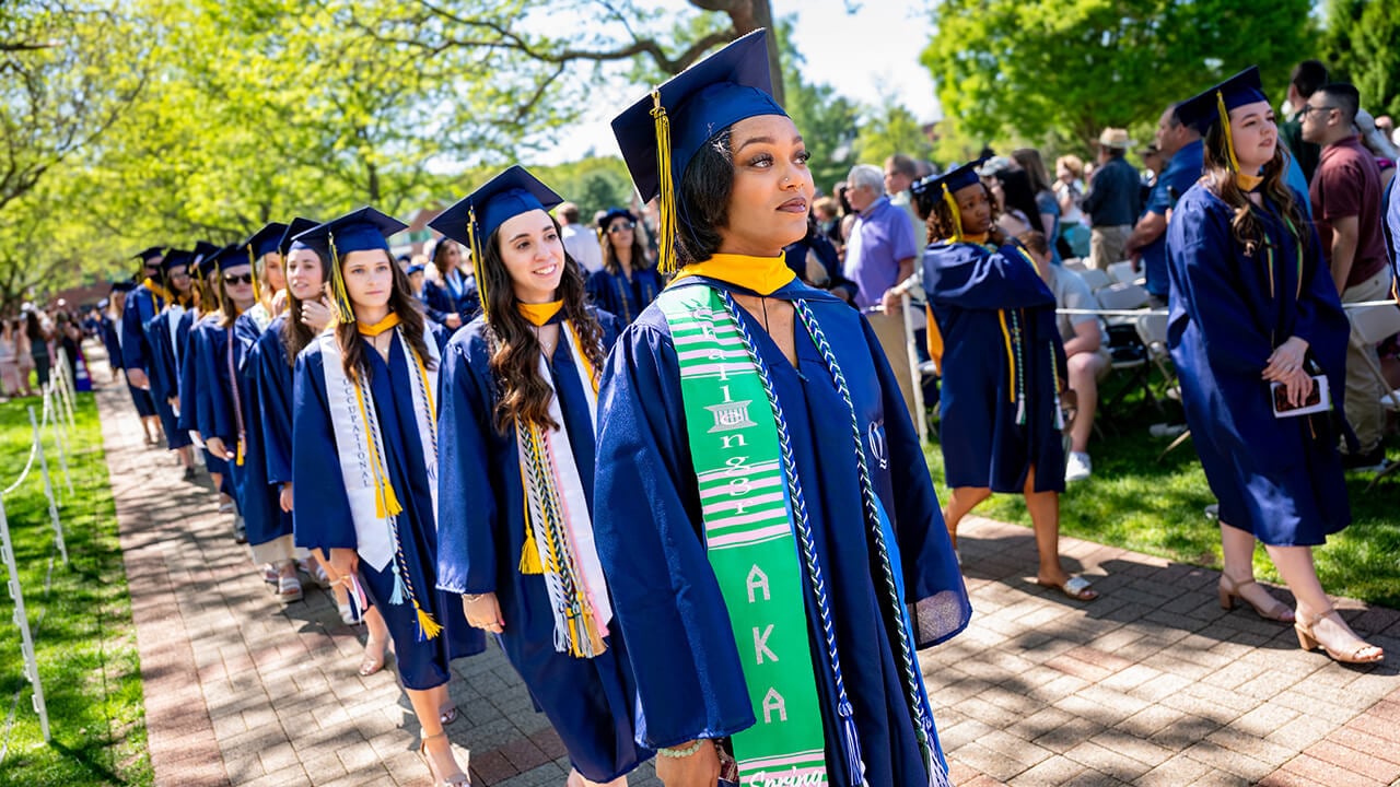 Sorority member wearing their letters, walking through the Quad on graduation