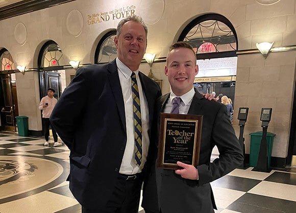Ryan Dombrowski smiling with teacher of the year plaque