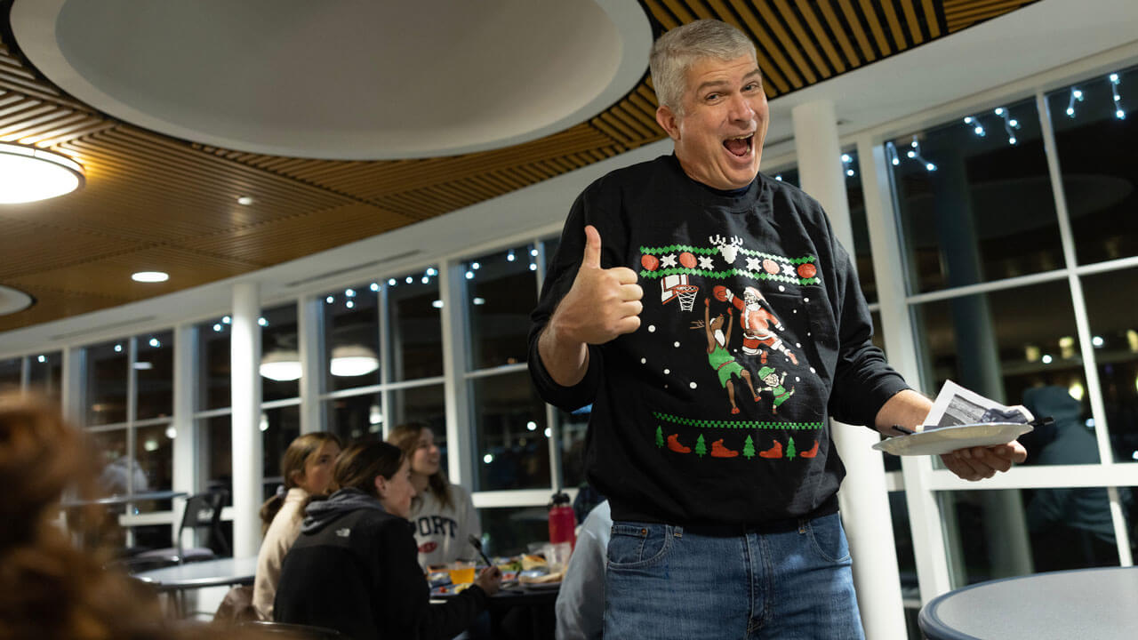 Dean Chris Roush gives a thumbs up while wearing a holiday sweater at the undergraduate holiday dinner.