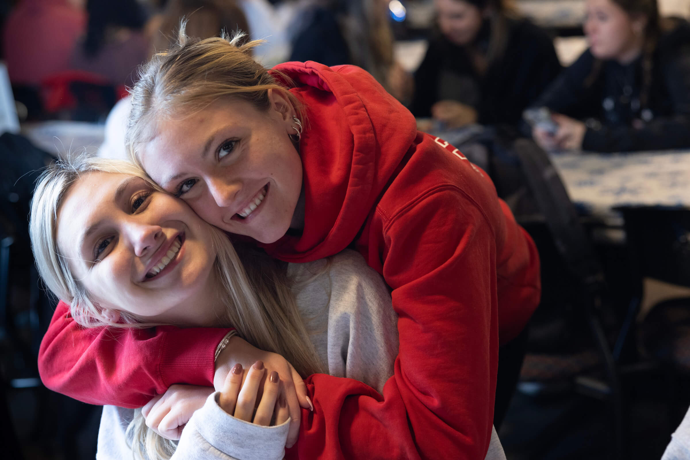 Two girls hug each other at the undergraduate holiday dinner.