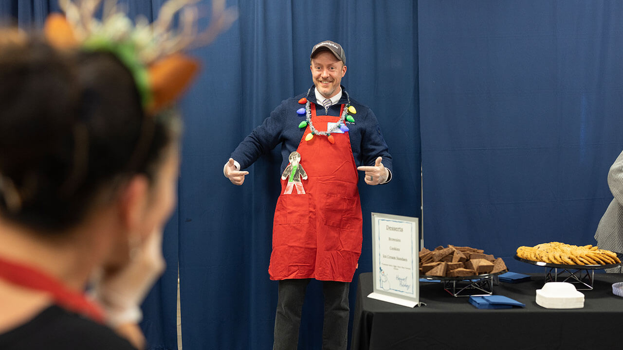 A volunteer smiles in his holiday themed apron