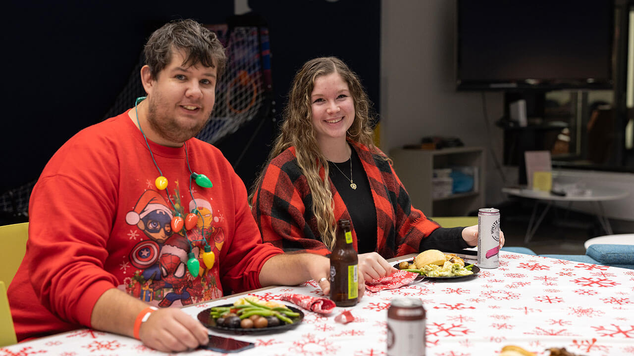 Two students sit down for dinner and drinks at the Annual Graduate Holiday Dinner