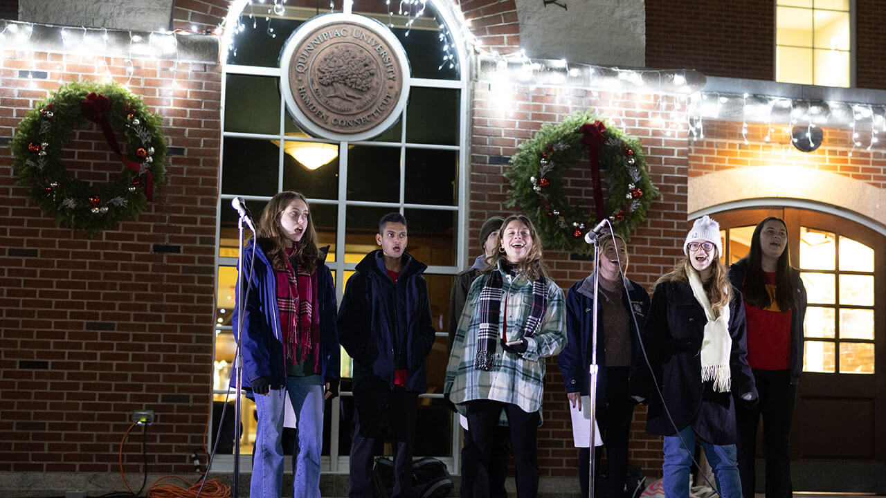One of Quinnipiac's a cappella groups sings holiday songs during the Quad lighting