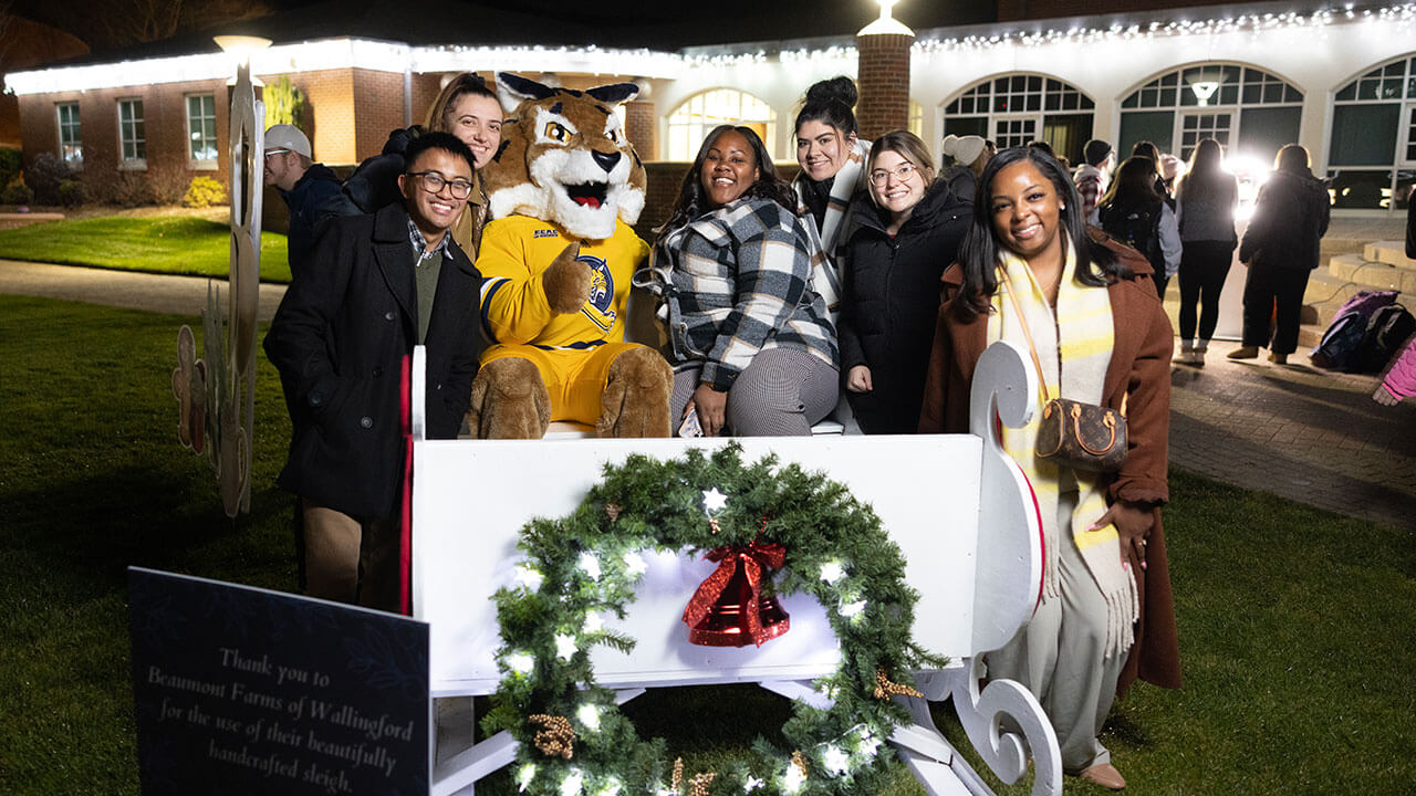 Students smile in excitement as they take a holiday photo with  Boomer