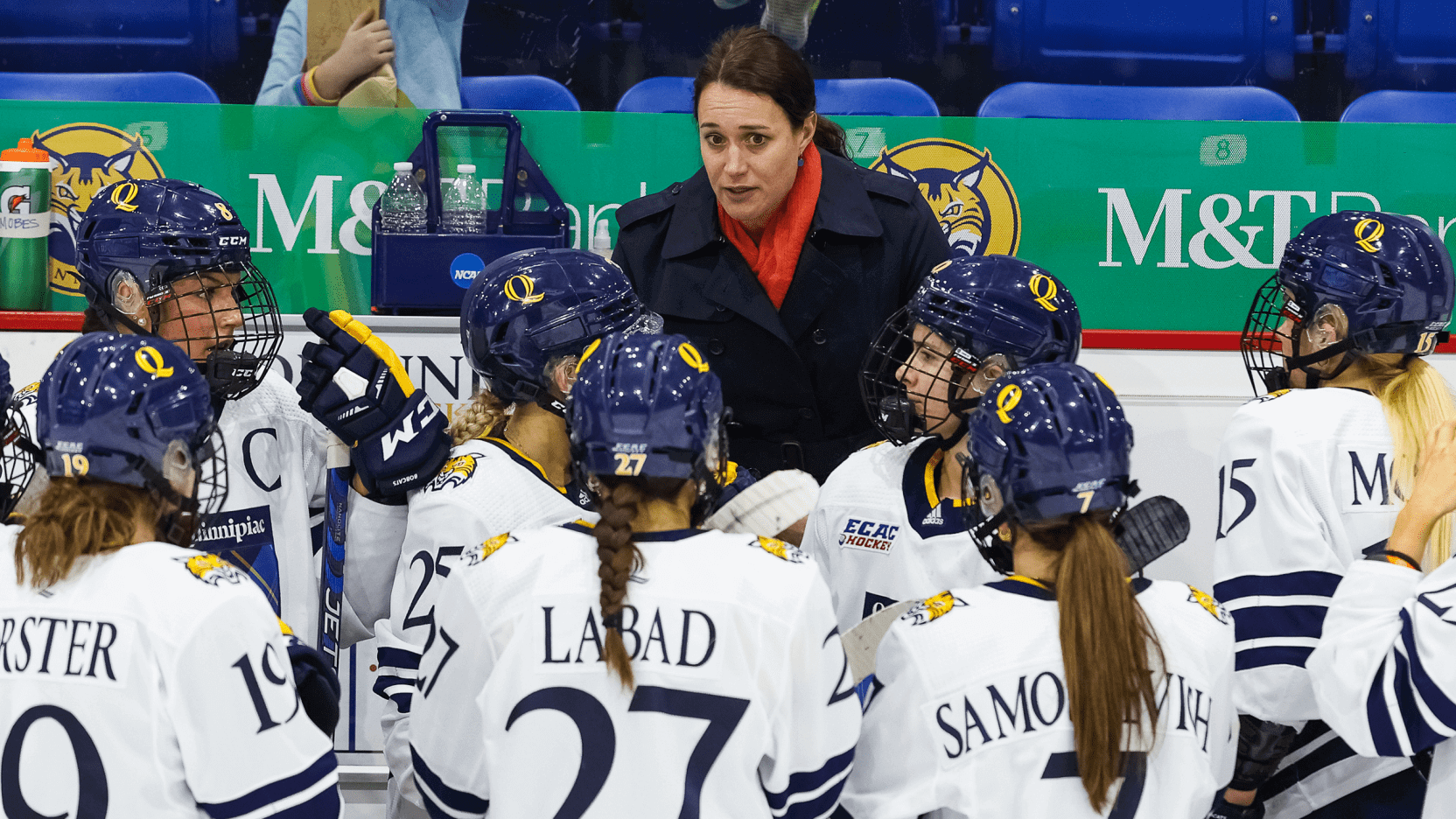Women's ice hockey head coach Cassie Turner stands on the bench talking to players