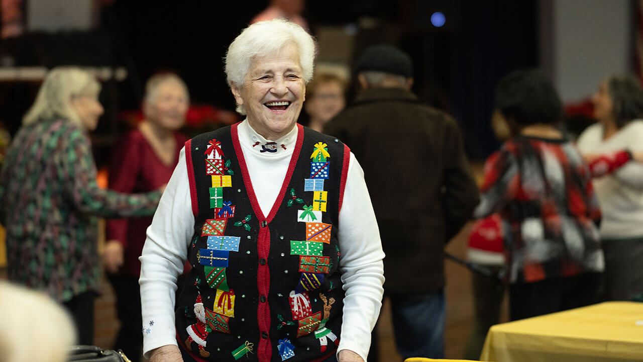 A Hamden senior citizen laughs while wearing a Christmas sweater.