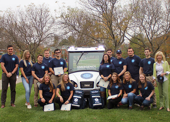 15 student EMTs and President Judy Olian with the EMS golf cart and 2 medical supplies backpacks.