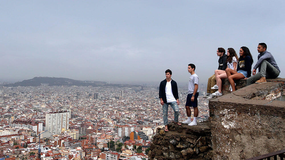 A group of Quinnipiac students stand on a ledge high above the city of Barcelona, Spain