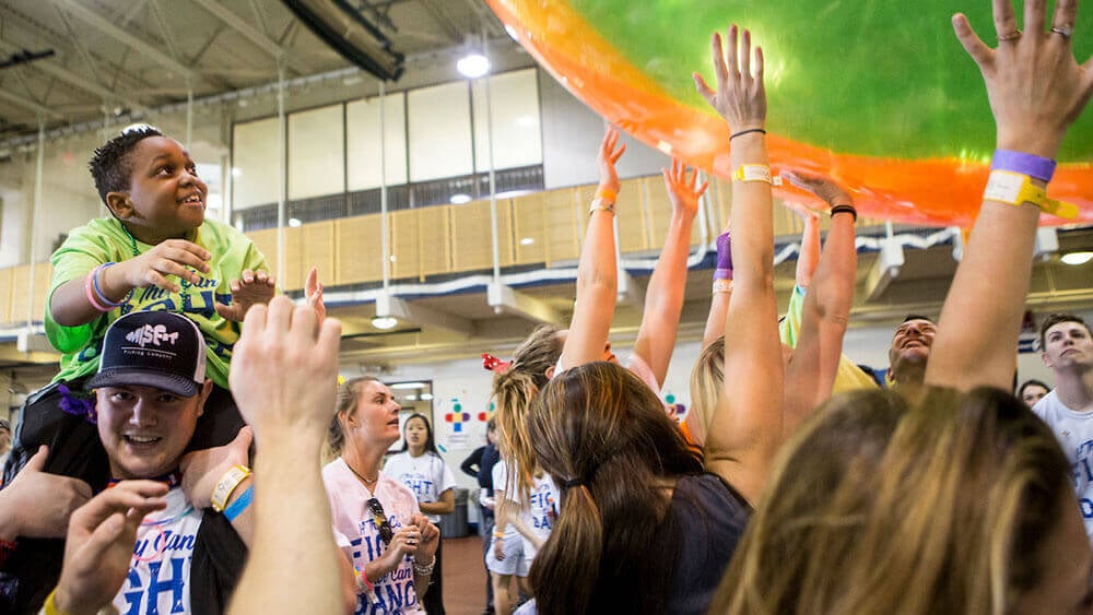 Students throw a giant neon green and orange beach ball around during a dance marathon competition
