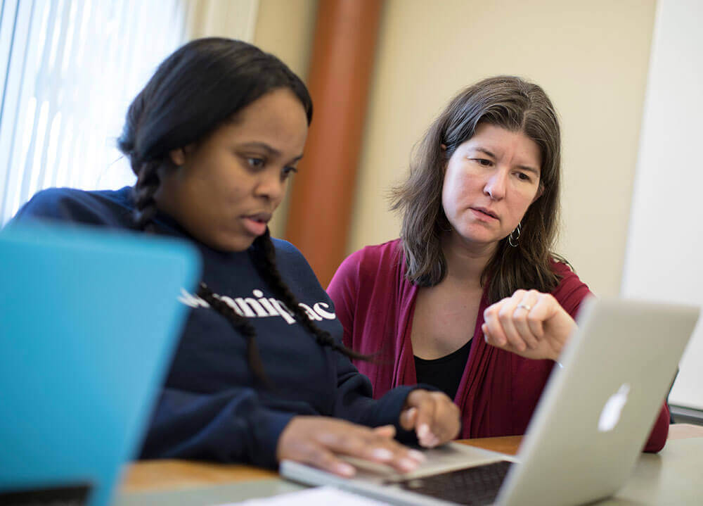 Sociology professor Catherine Solomon sits next to a student and assists with classwork