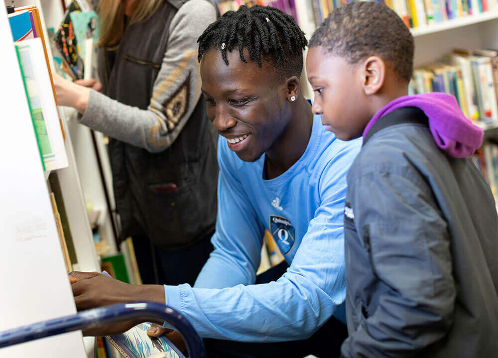 Sociology student Abdulai Bundu assists a child in picking out a book at a library