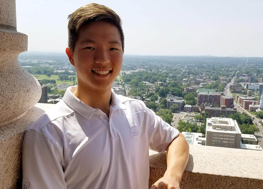 Economics student James Burnahm smiles from the observation deck of the Travelers Tower with a view of Hartford in the background