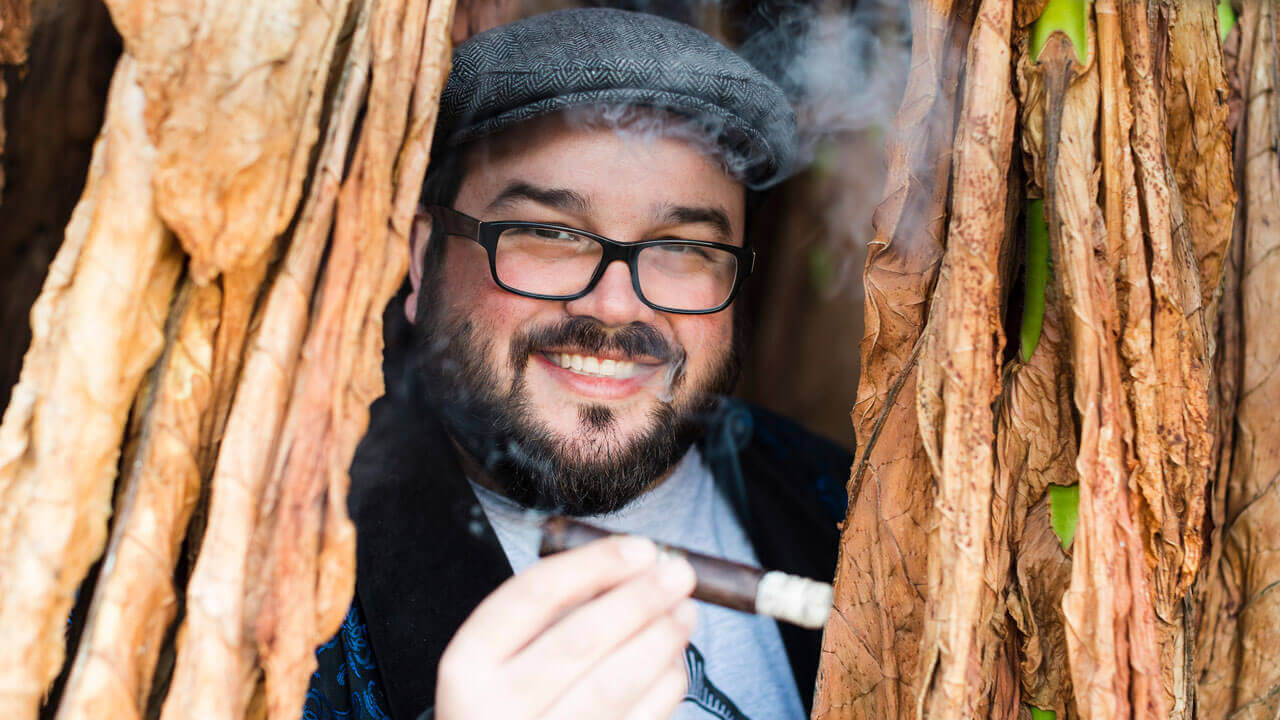 Nicholas Melillo smiles while holding a cigar