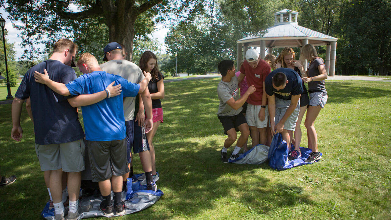 Students huddle into two teams in a field