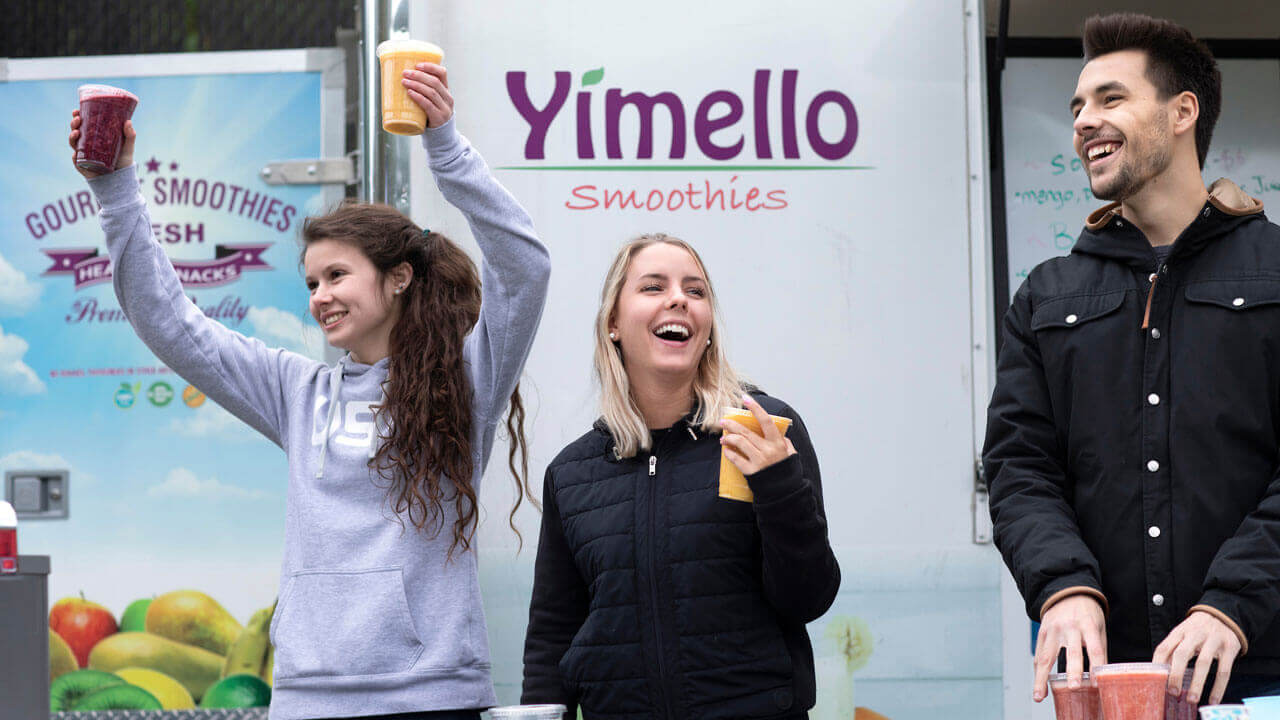 Three students hold smoothies to sell to others