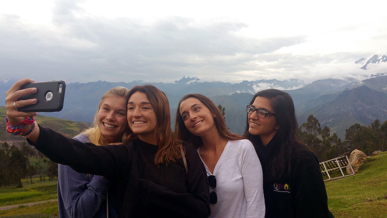 Four students take a selfie from atop a Peruvian mountain