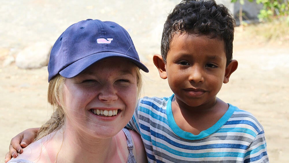 A journalism student and a Nicaraguan boy smile on the beach