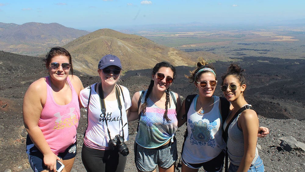 A group of journalism students pose in front of a Nicaraguan mountain range