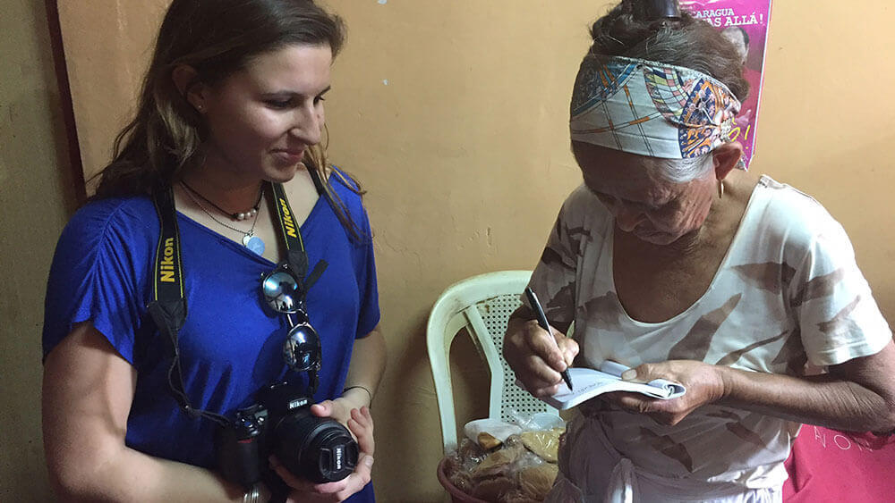 A journalism student takes notes while interviewing a Nicaraguan woman