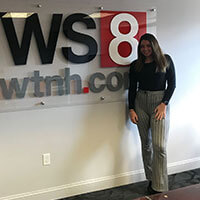 Carlye Paskow standing in front of the WTNH News Channel 8 sign